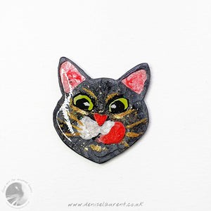 Yum! A black cat pin. A black cat face with big green eyes and gold whiskers, licking his lips. A handmade, one-of-a-kind pin.