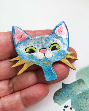 A unique handmade cat brooch from my catitude series.  She is a blue cat with green eyes, a cute pink nose and gold whiskers. A whimsical, fun cat face brooch.