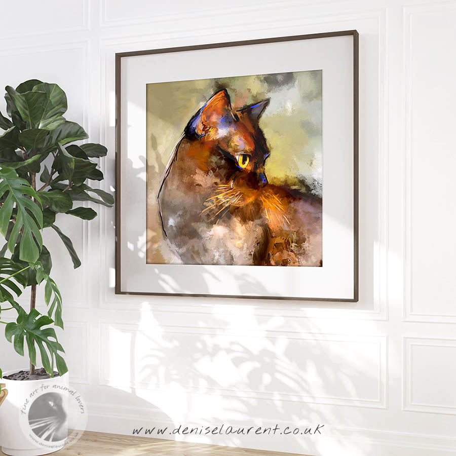 Semi-abstract, contemporary Burmese cat wall art. She is a brown cat with yellow eyes, a strong expression and a warm green background. She is framed and hanging on a wall in a sunny room.