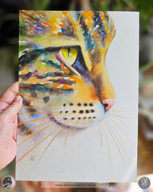 Colorful watercolor painting of a tabby cat's face held by a hand.