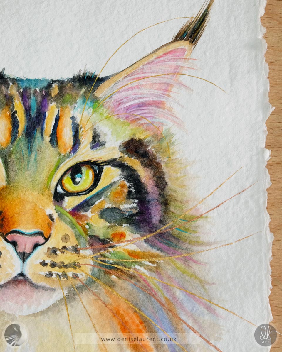 Close up of a watercolor painting of a tabby cat's face on handmade paper showing her gold and copper whiskers and details of the deckled paper edges.