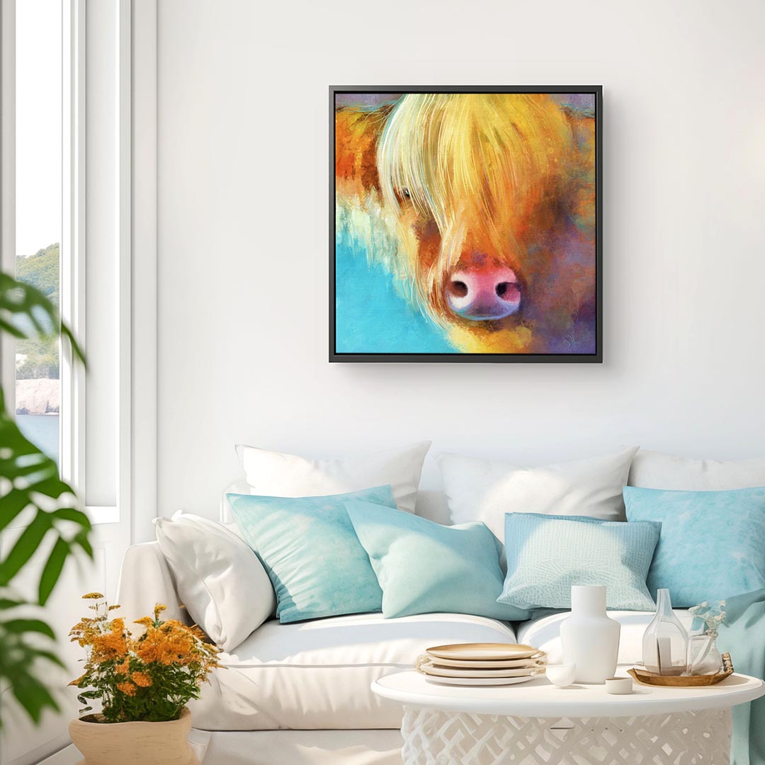 Highland cow wall art featuring a blonde coo with a long fringe, in warm summer colours and framed in a wood floater frame.