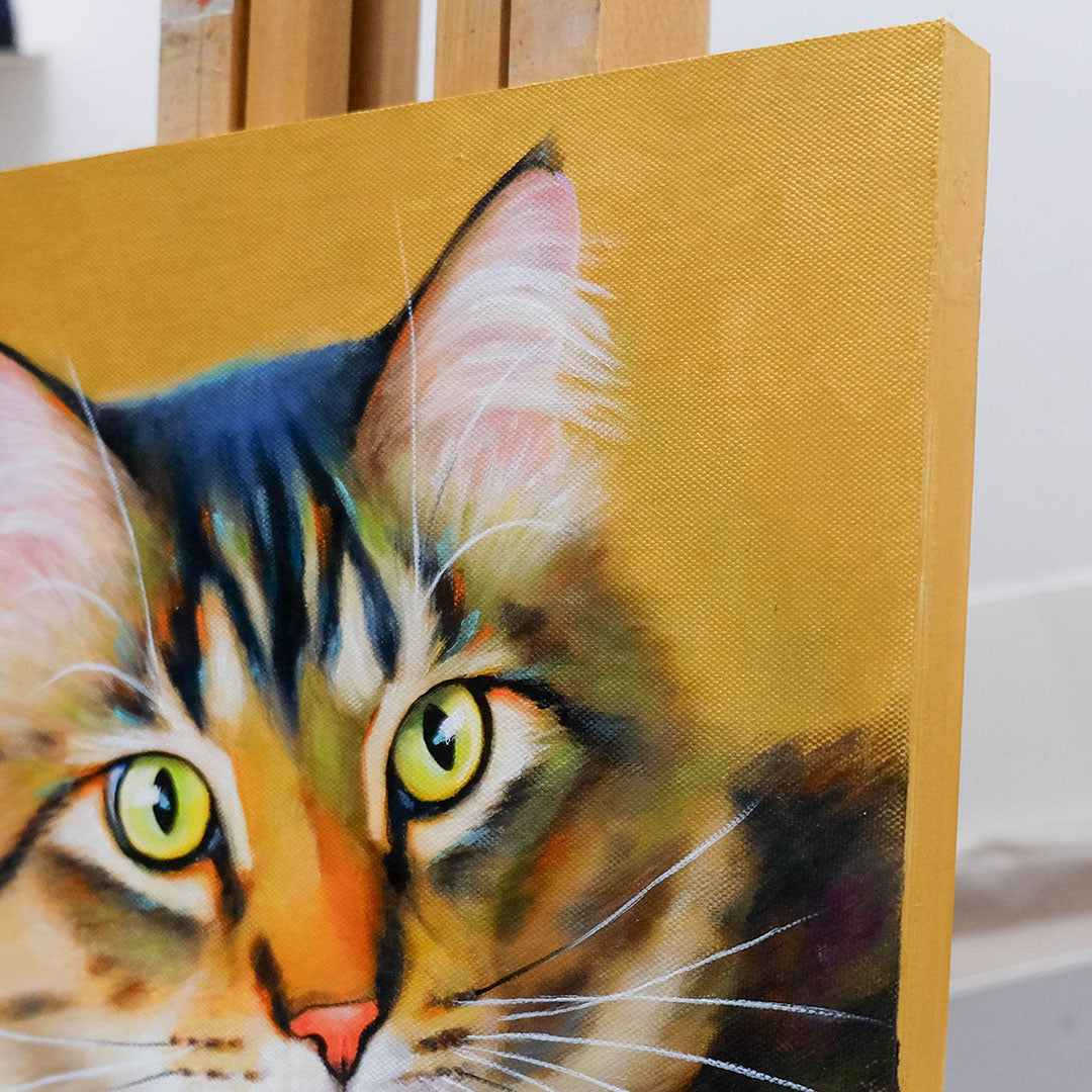 Close-up of a painting of a cat's face on a gold background with gold edges of the panel