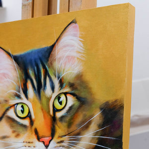 Close-up of a painting of a cat's face on a gold background with gold edges of the panel