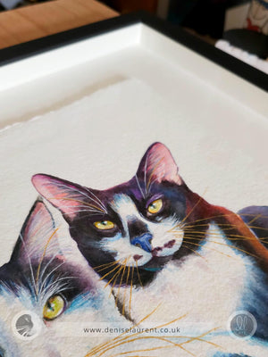 Closeup of a framed artwork of two cats, Toots & Evie, on handmade paper, framed in a shadowbox frame so that the paper 'floats' in the frame. 