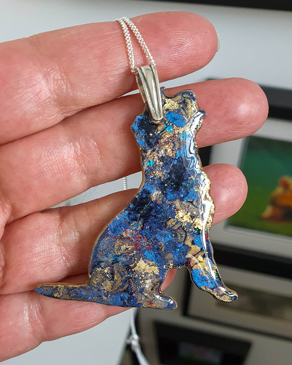 Border terrier dog-shaped necklace. One side of a double sided pendant. This side is blues and golds with lots of sparkle like a starry night sky.