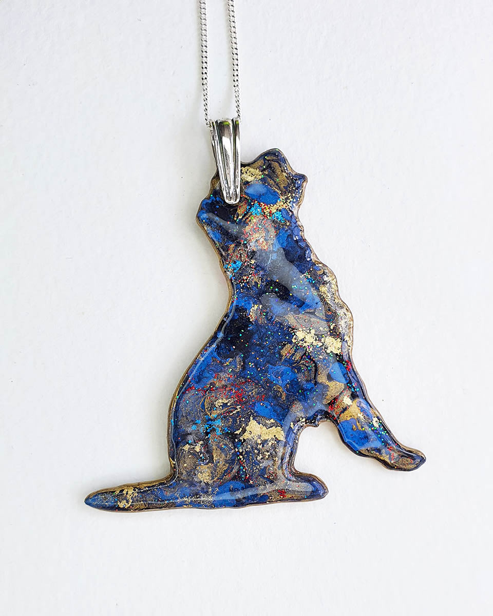 Border terrier dog-shaped necklace with a colorful design of blues and golds on a white background