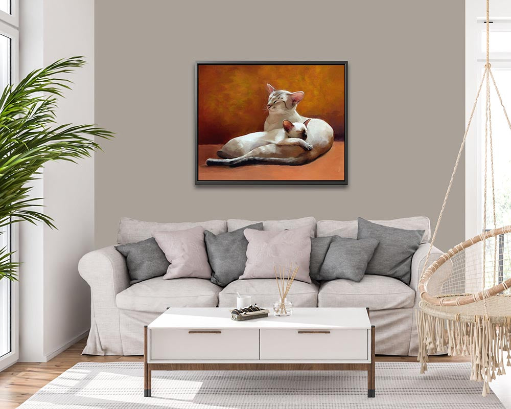 Father and Daughter - Framed Canvas Print showing a serene scene of a Siamese cat and kitten snuggling together, on an orange sofa, perfect for a warm and inviting home decor. 