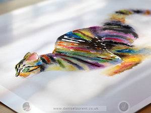 A colorful print from a watercolour painting of a running tabby cat on white paper, with soft shadows across the artwork. The cat is depicted in a side profile with a vibrant mix of colors including yellow, green, blue, pink, purple, and black.