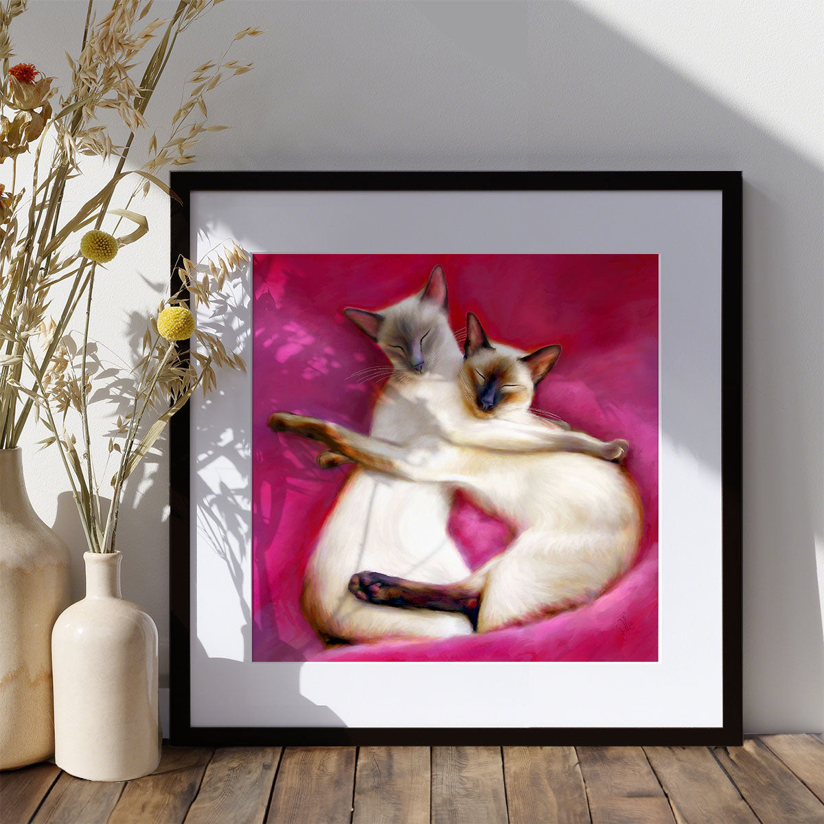fine art print of a pair of siamese cat with their arms around each other on pink cushions