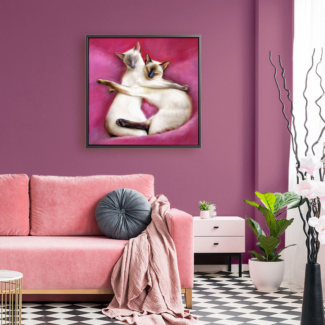 Siamese cat framed canvas featuring two siamese cats cuddling each other on pink cushions.