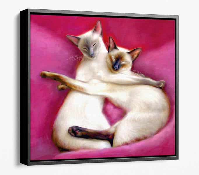 Siamese cat framed canvas featuring two siamese cats cuddling each other on pink cushions.