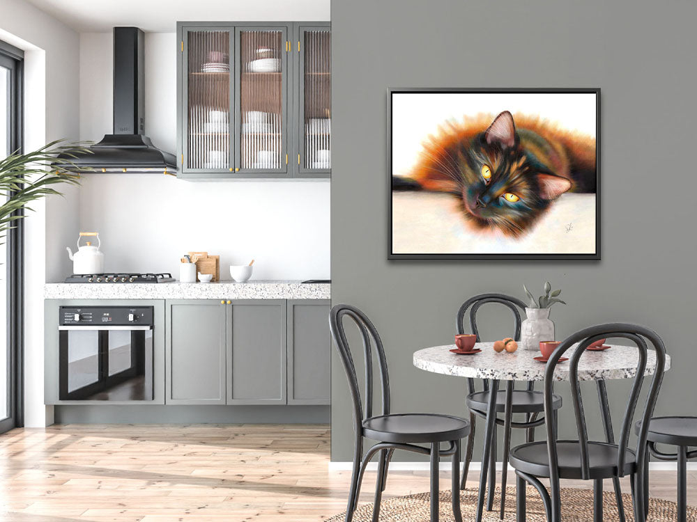 'Sunbathing' framed canvas, a beautiful tortoiseshell cat artwork featuring a long-haired cat with yellow eyes and a rich, multi-coloured coat, lying in the sun. The sun gives her a golden halo in her fur. 